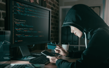 hacker looking at phone by a computer screen, Cybersecurity, Ransomware Protection