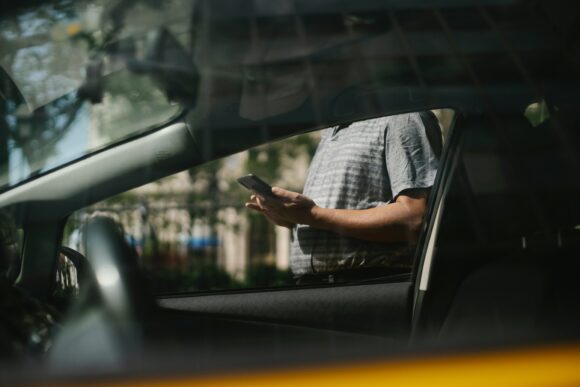 Man with cell phone by car, LeadingIT, Cybersecurity